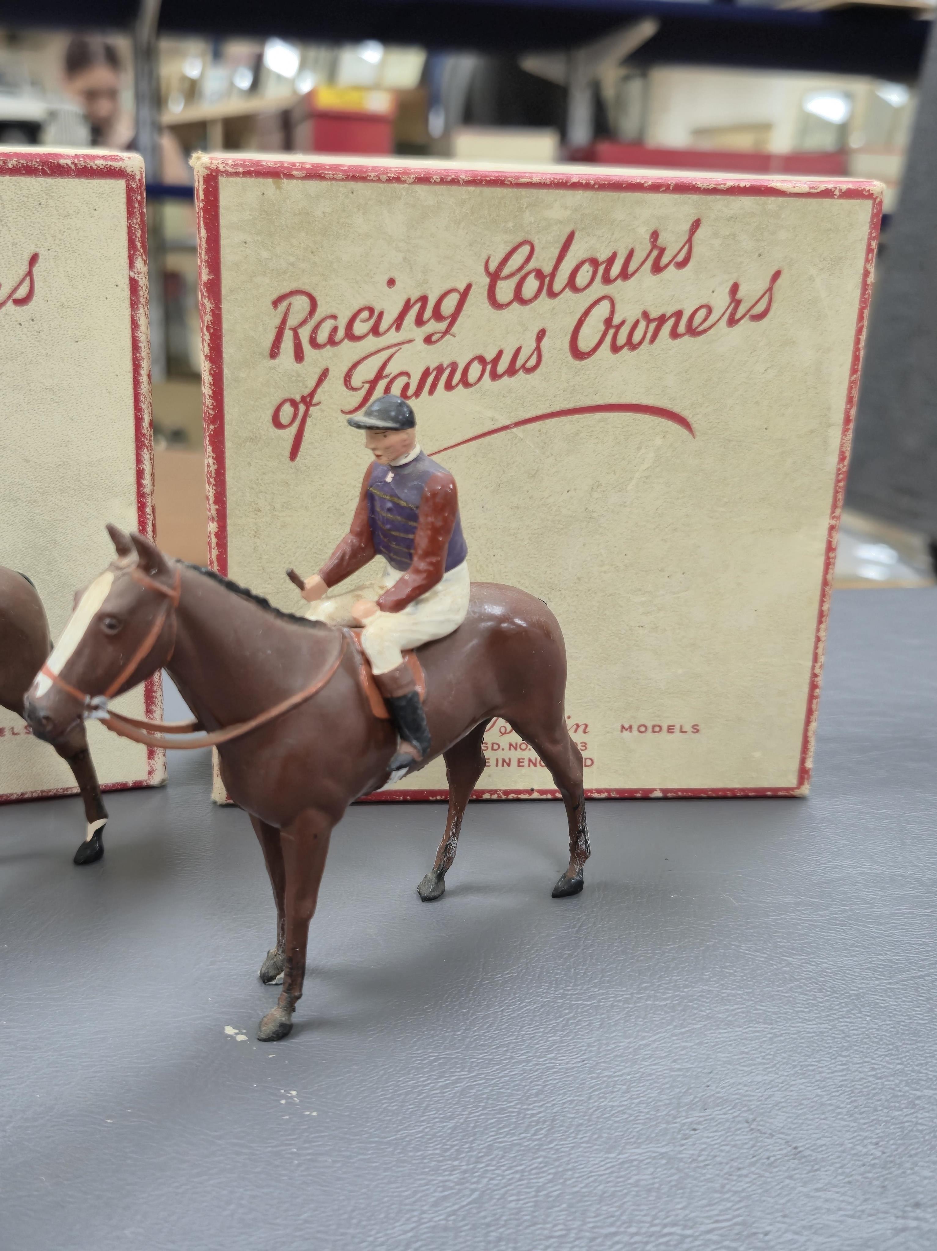 Two boxed Britains Racing Colours of Famous Owners series lead mounted figures; H.M. The Queen - rider in purple and brown jersey with gold frogging on a brown horse, and H.H. The Aga Khan - rider in dark green jersey on